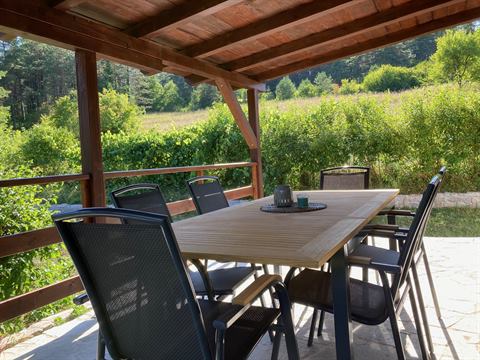 Terrasse mit Tisch und Stühlen und Blick ins grüne Tal